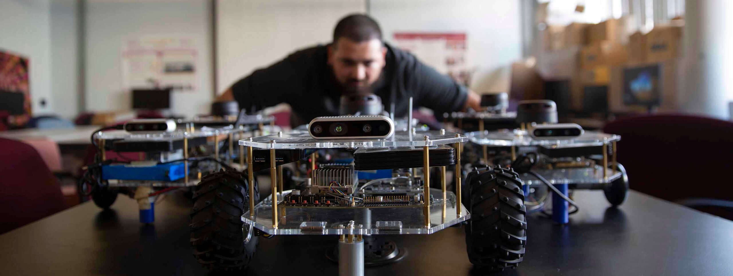 A student examines a wheeled robotics project