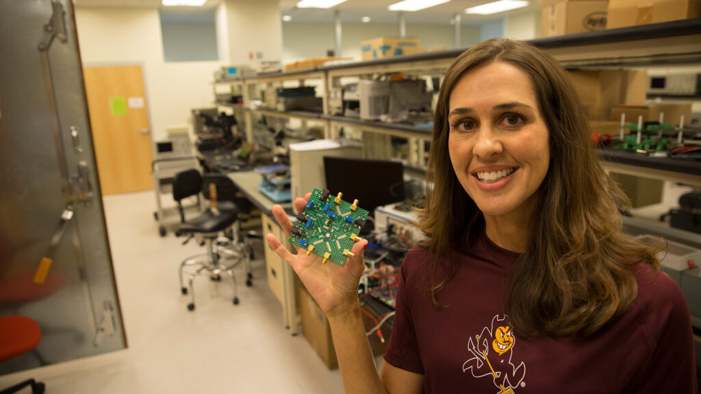 Jennifer Kitchen holds a semiconductor chip up to the camera