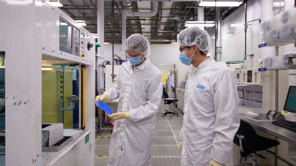 Two researchers examine a solar cell in the MacroTechnology Works facility